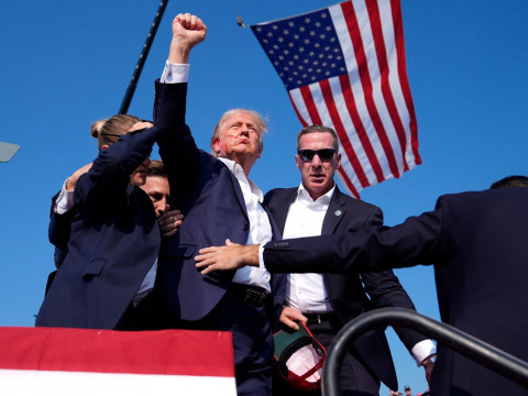 Donald Trump volt amerikai elnök, a Republikánus Párt elnökjelöltje feltartja kezét, miközben a védelmét ellátó titkosszolgálat ügynökei körbe veszik a Pennsylvania állambeli Butlerben rendezett kampánygyűlésen 2024. július 13-án (Fotó: MTI/AP/Evan Vucci)