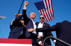 Donald Trump volt amerikai elnök, a Republikánus Párt elnökjelöltje feltartja kezét, miközben a védelmét ellátó titkosszolgálat ügynökei körbe veszik a Pennsylvania állambeli Butlerben rendezett kampánygyűlésen 2024. július 13-án (Fotó: MTI/AP/Evan Vucci)